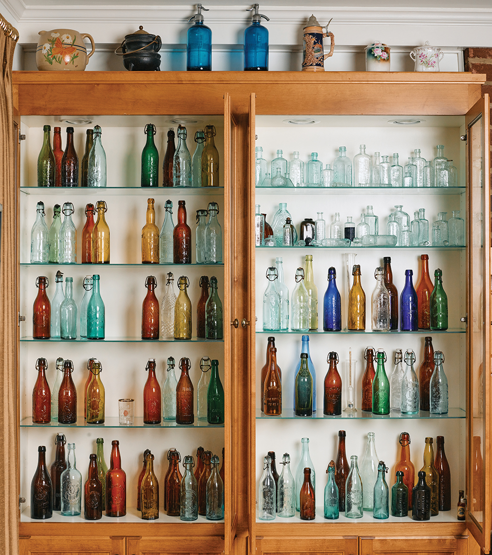 Antique bottle collection displayed in wooden cabinet showcasing historical glass treasures